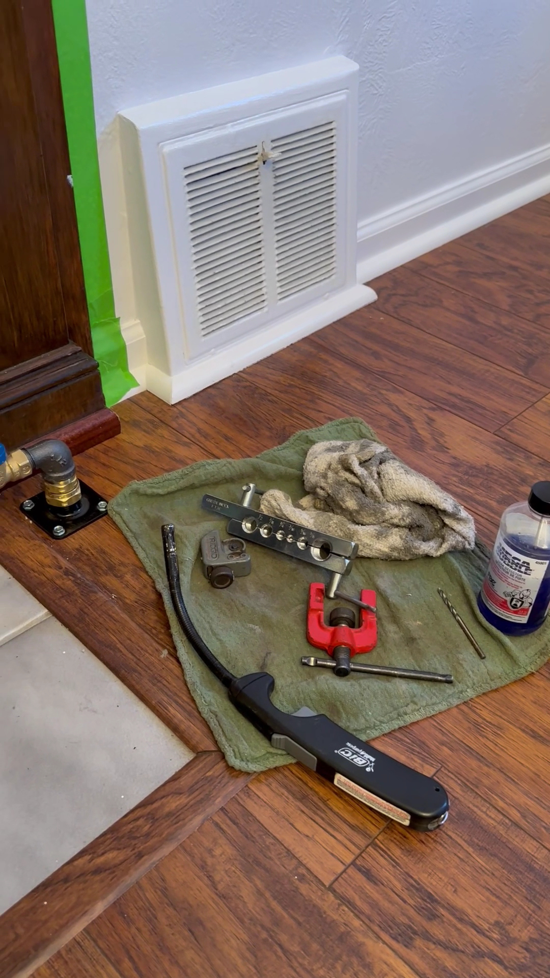Gas line stub-out work with pipe-threading tools laid out in a hardwood-floor home